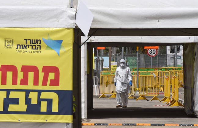 A member of Magen David Adom wears protective clothing while working in a coronavirus drive through tent in Jerusalem, on Friday, March 27, 2020. Eleven Israelis have died from the coronavirus, while more than 3,000 have been diagnosed with the disease. The Israeli government has imposed tight restrictions of movement, leaving only essential stores open in an effort to stop the spread of the coronavirus.  JER2020032713 DEBBIExHILL
