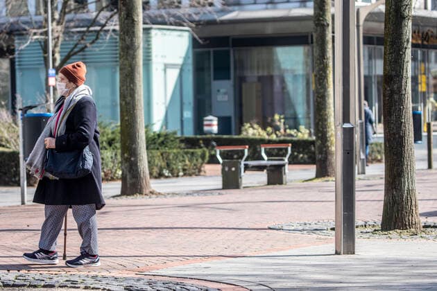 27 03 2020, DU Duisburg , Corona paralyzes Duisburg city center , People with mouthguards on the way , Homeless people in groups on the way , Police checks an elderly lady with mouthguard on the way in the city center