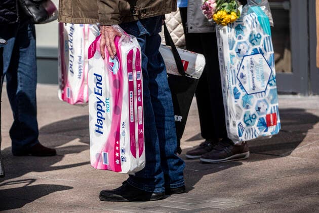 27 03 2020, DU Duisburg , Corona paralyzes Duisburg city center , People wearing face masks , Homeless people in groups , Police checks people in front of a supermarket in the city center with large packages of toilet paper in their hands