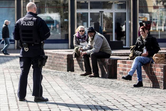 27 03 2020, DU Duisburg , Corona paralyzes Duisburg city center , People with mouthguards on the way , Homeless people in groups on the way , Police checks the homeless people at the fountain at the cow gate in the city center