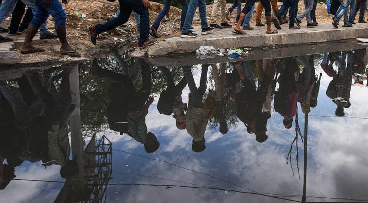 NEW DELHI, INDIA - MARCH 27: A reflection of migrant workers seen on a waterlogged pavement as many workers head home on the third day of national lockdown imposed by Prime Minister Narendra Modi to curb the spread of Coronavirus COVID-19 , at Ghazipur, on March 27, 2020 in New Delhi, India. (Photo by Amal KS Hindustan Times) Hit By Lockdown, Migrant Workers Walk To Reach Homes