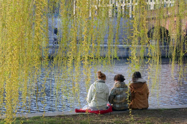 27 03 2020, Berlin Germany Corona crisis, these three young women do not care about the contact restriction to two persons, they enjoy the beautiful weather on the banks of the Spree