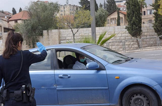 An Israeli police stops cars, as part of coronavirus restrictions, outside the Old City of Jerusalem, on Saturday, March 28, 2020. The Israeli government has imposed tight restrictions of movement, leaving only essential stores open in an effort to stop the spread of the coronavirus disease.  JER2020032802 DEBBIExHILL