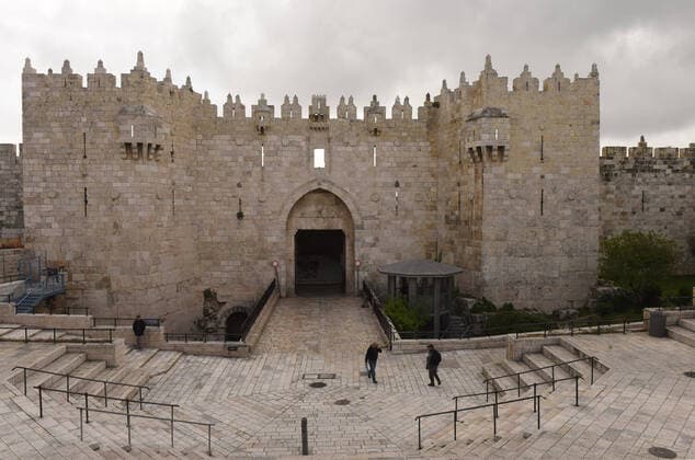 Few Palestinians walk outside the Damascus Gate of Jerusalem s Old City, in compliance with coronavirus movement restrictions, on Saturday, March 28, 2020. The Israeli government has imposed tight restrictions of movement, leaving only essential stores open in an effort to stop the spread of the coronavirus disease.  JER2020032806 DEBBIExHILL