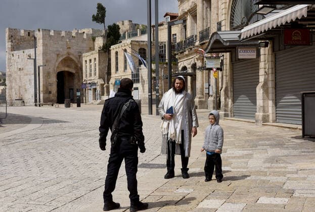 An Israeli police stops an Ultra-Orthodox Jew and his son from entering the Jerusalem s Old City, in compliance with coronavirus movement restrictions, on Saturday, March 28, 2020. The Israeli government has imposed tight restrictions of movement, leaving only essential stores open in an effort to stop the spread of the coronavirus disease.  JER2020032820 DEBBIExHILL