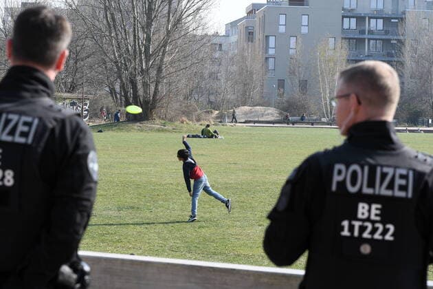 Berlin police officers make loudspeaker announcements and ask everyone who is sitting or lying on the meadow to move away.