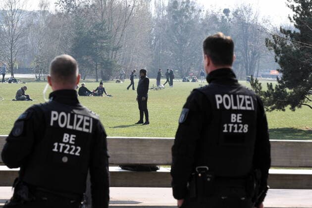 Berlin police officers make loudspeaker announcements and ask everyone who is sitting or lying on the meadow to move away.