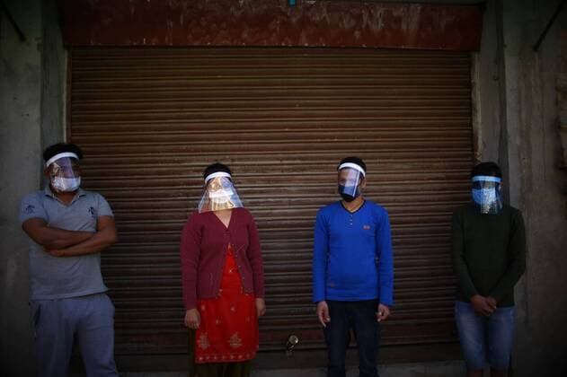 (200328) -- KATHMANDU, March 28, 2020 -- Photo taken on March 28, 2020 shows locals wearing face shields in front of a closed door in Kathmandu, Nepal. Nepal, facing the shortage of test kits and personal protective equipment for health workers, has recorded five confirmed cases of the COVID-19 so far. (Photo by Xinhua) NEPAL-KATHMANDU-COVID-19-HOMEMADE FACE SHIELD SulavxShrestha 