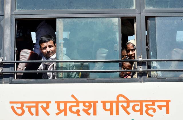 NEW DELHI, INDIA - MARCH 28: Migrant workers peep out of a bus window as they leave for their native state at Kaushambi Roadways Bus Stand on Day 4 of the 21 day nationwide lockdown to check the spread of coronavirus, at Kaushambi, on March 28, 2020 in New Delhi, India. (Photo by Ajay Aggarwal Hindustan Times ) Coronavirus Update: Amid Lockdown, A Sea Of Migrants In Delhi-NCR Try To Find Their Way Back Home