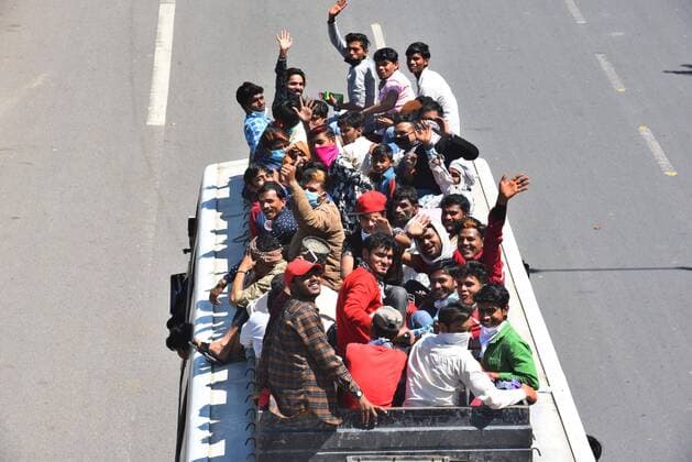 NEW DELHI, INDIA - MARCH 28: Migrant workers wave from on top of a bus bound to their native state, at Ghazipur, near the Delhi - UP border on Day 4 of the 21 day nationwide lockdown -- to check the spread of coronavirus, on March 28, 2020 in New Delhi, India. (Photo by Raj K Raj Hindustan Times ) Coronavirus Update: Amid Lockdown, A Sea Of Migrants In Delhi-NCR Try To Find Their Way Back Home