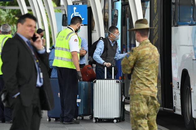 AUSTRALIA CORONAVIRUS COVID-19, A member of the Defence Force watches over as returning overseas travellers are ushered towards waiting busses for the beginning of their 14-day imposed quarantine after arriving at Sydney International Airport in Sydney, Sunday, March 29, 2020. ( NO ARCHIVING, EDITORIAL USE ONLY, NO USE IN BOOKS WITHOUT CONSENT SYDNEY NSW AUSTRALIA  Copyright: xJOELxCARRETTx 20200329001460669590