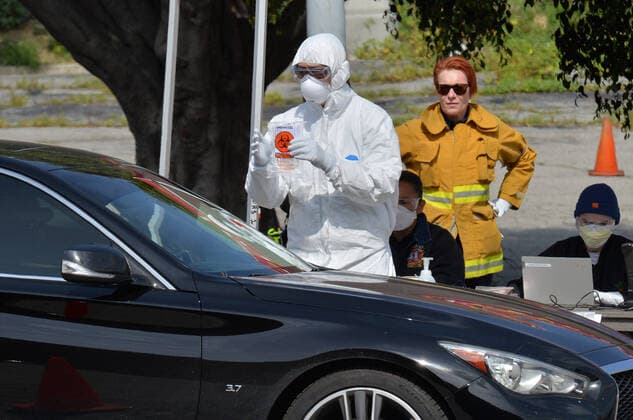 Medical and fire department personnel distribute self-testing coronavirus kits to residents who made appointments, in a parking lot adjacent to Dodger Stadium in Los Angeles on Saturday, March 28, 2020. The number of confirmed cases of COVID-19, the disease caused by the.coronavirus in Los Angeles County stood at 1,465 as of midday Saturday, with 26 deaths. The county s Department of Public Health reported 257 new cases on Friday, and 421 on Thursday, the highest one-day total so far.  LAP2020032819 JIMxRUYMEN