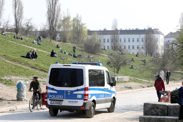 28 03 2020, Berlin Germany the warm weekend draws people outside in the Corona crisis The police patrol in Mauerpark People follow the rules and sit outside in the sun