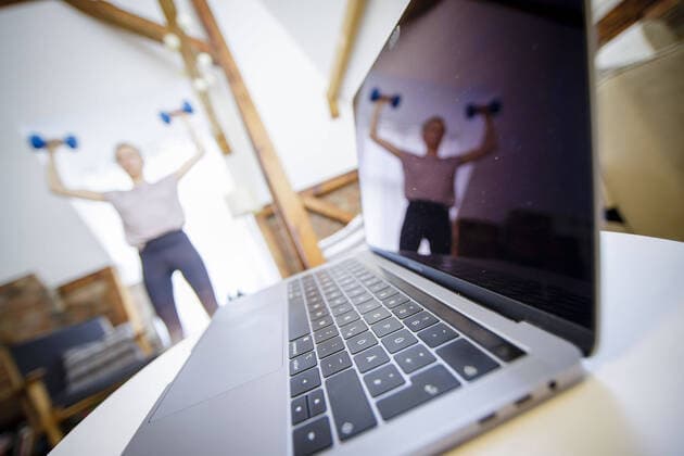 Symbolic photo on the subject of fitness A woman is exercising at home with dumbbells Next to her is a laptop Berlin, 26 03 2020 Berlin Germany Copyright: xphotothek xThomasxTrutschelx