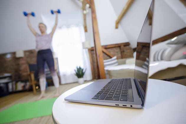 Symbolic photo on the subject of fitness A woman is exercising at home with dumbbells Next to her is a laptop Berlin, 26 03 2020 Berlin Germany Copyright: xphotothek xThomasxTrutschelx