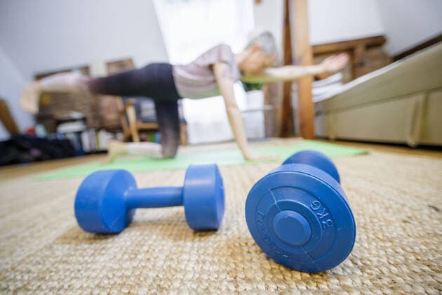 Symbol photo on the subject of fitness A woman is exercising at home in her living room In front of her are two dumbbells Berlin, 26 03 2020 Berlin Germany Copyright: xphotothek xThomasxTrutschelx