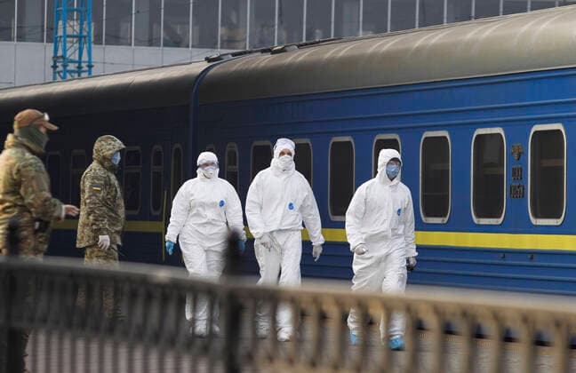 March 29, 2020, Kiev, Ukraine: Ukrainian border guard officers wearing protective suits as a preventive measure, walk past a train with Ukrainian citizens after the evacuation..The special train from Kiev to Moscow evacuated Russian citizens to Moscow on 27 March 2020, and brought back Ukrainian citizens from Moscow to Kiev on 29 March 2020, after Ukrainian authorities shut the country s borders amid the spread of the COVID-19 coronavirus pandemic. Kiev Ukraine - ZUMAs197 20200329_zaa_s197_075 Copyright: xPavloxGoncharx