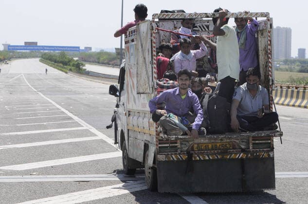 NOIDA, INDIA - MARCH 29: Migrant workers headed back to their towns and villages hitch a ride, on day 5 of the nationwide lockdown imposed by PM Narendra Modi to check the spread of coronavirus, at Yamuna expressway zero point, on March 29, 2020 in Noida, India. (Photo by Sunil Ghosh Hindustan Times ) Migrant Workers Head Home In Coronavirus Lockdown