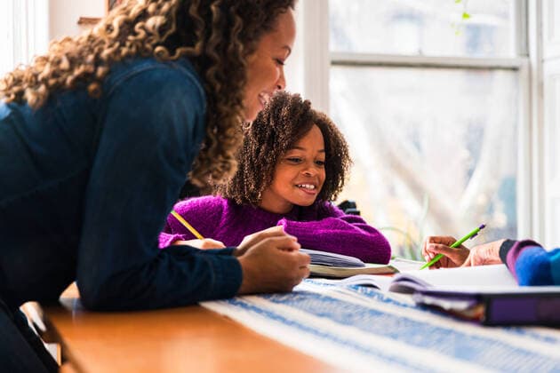 Creative Highlights Symbol Smiling mother assisting daughters in doing homework at home New York, NY, United States ,model released, Symbolfoto ,property released CR_LIWEEE200227-318349-01