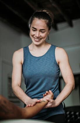 Smiling massage therapist treats her patient s hand and arm Portland, ME, United States ,model released, Symbolfoto CR_SSNF200227-305982-01