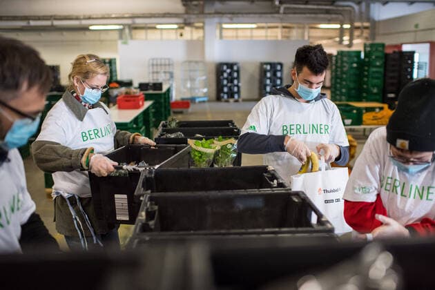 Berlin Corona-Krise Berliner Tafel Auswirkungen der Corona-Krise. Die Corona-Situation hat auch fuer die Hilfsorganisation Berliner Tafel weitreichende Konsequenzen. 42 LAIB und SEELE-Ausgabestellen mussten schliessen, nur drei der Ausgabestellen haben noch geoeffnet. Rund 50.000 beduerftige Menschen kommen ueblicherweise jeden Monat an den Ausgabestellen. Damit die Menschen weiterhin gespendete Lebensmittel erhalten koennen, beliefert die Berliner Tafel nun die Menschen zu Hause. In einer Halle auf dem Berliner Grossmarkt packen freiwillige Helferinnen und Helfer Tueten mit Lebensmitteln (im Bild), die verteilt werden. In einigen Bezirken uebernehmen Radfahrerinnen und Radfahrer der Rebel Riders mit Lastenraedern die Vor-Ort-Verteilung von Tuer zu Tuer. LAIB und SEELE ist eine Aktion der Berliner Tafel e.V., der Kirchen u