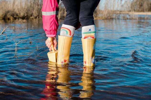 child s feet in rain boots in the water with a spade playing NorrtoÂ¤lje, Stockholm County, Sweden ,model released, Symbolfoto CR_RABE200320-317775-01