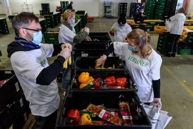 In a hall of the Berlin wholesale market, volunteers of the Berliner Tafel pack food in bags with respirator masks Respirator Mask Food in bags Because of the COVID 19 pandemic, the 42 LAIB and SEELE distribution points had to close So that needy people can continue to receive donated food, the Berliner Tafel now supplies the needy at home snapshot photography F Boillot