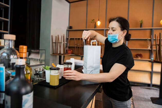 Izabela Rosiak packs cocktails for delivery in a bag in the bar in