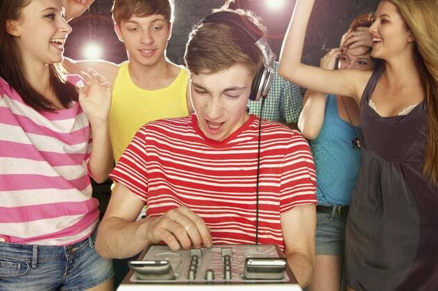 Teenage boy DJ playing music for friends dancing at party England Kent  Copyright: JuttaxKlee fStopImages1889018