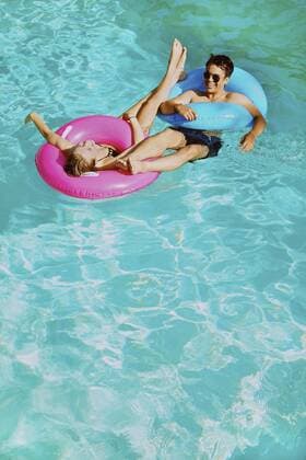 Happy young couple with inflatable rings in sunny summer swimming pool England Kent  Copyright: JuttaxKlee fStopImages1889052