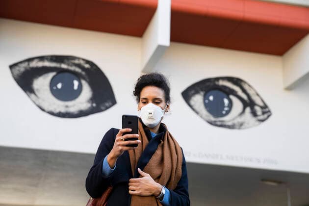 Eine Junge Frau schaut aud ihr Handy mit den Augen eines Grafitti im Hintergrund am 1. April 2020. Um die Verbreitung des Coronavirus (SARS-CoV-2) zu verlangsamen beschlossen Bund und Laender weitere Restriktionen. Nachdem Museen, Theatern, Sportveranstaltungen usw verboten wurden sind seit einigen Tagen weitere verschaerfte Massnahmen in Kraft getreten wie z.B. Verbot von Versammlungen in der Oeffentlichkeit mit mehr als zwei Personen, Einhaltung von Mindestabstand zwischen Personen und Schliessung von Gastronomiebetrieben mit Ausnahme von Abholung und Lieferung. Es wird diskutiert ob die Nutzung und Auswertung oder gar die Kontrolle der Handydaten zur Eindaemmung der Verbreitung der Virus mit der Verfassung und den Respekt der Grundrechte sei. Achtung: Illustrative Editorial. MR = Yes Diskussion ueber moegliche Kontrolle von Handydaten