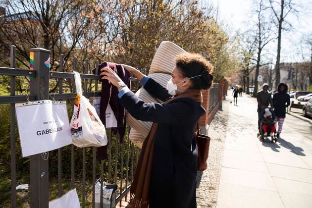 A young woman wraps a sweater on a Gabon fence in Berlin on 1 April 2020 To slow the spread of the corona virus SARS CoV 2, the federal and state governments decided to impose further restrictio