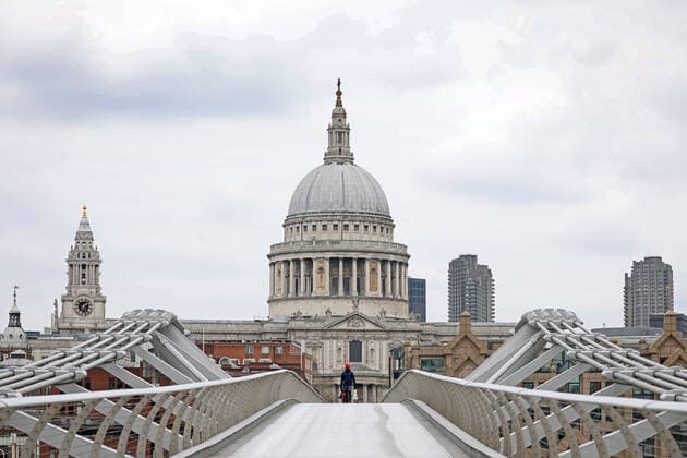 Day Nine of Lockdown in London. A person walks across the Millennium Bridge with St. Paul s Cathedral in the background. The country is on lockdown due to the COVID-19 Coronavirus pandemic. People are not allowed to leave home except for minimal food shopping, medical treatment, exercise - once a day, and essential work. COVID-19 Coronavirus lockdown, London, UK, on April 1, 2020 