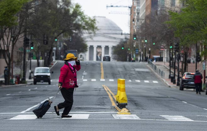 A person crosses sixth street near the National Gallery of Art after the DC Government issues a stay at home order to help combat the spread of the Coronavirus, COVID-19, pandemic, in Washington, D.C. on Wednesday, April 1, 2020.  WAP20200401321 KEVINxDIETSCH