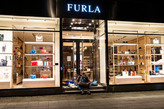 A homeless man, who has made his temporary accommodation at the entrance of a boutique for luxury bags Furla, reads the newspaper at the Kudamm in Berlin on April 1, 2020 To slow do
