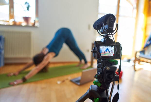 Kaufbeuren, Germany, April 01, 2020. Yoga teacher teaches customers in a online course and live streaming with computer and iphone due to the Corona virus disease (COVID-19) on April 01, 2020 in Kaufbeuren, Germany Model released
