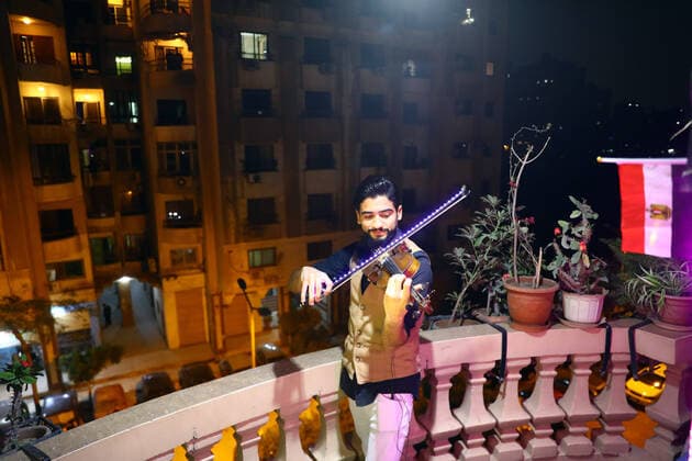 (200402) -- CAIRO, April 2, 2020 -- Egyptian violinist Mohammed Adel plays the violin during his balcony concert in Cairo, Egypt on March 31, 2020. Every night, Egyptian violinist Mohammed Adel gives a live concert from his balcony to entertain his neighbors during a coronavirus-caused nationwide nighttime curfew. TO GO WITH: Feature: Egyptian violinist s balcony performances amuse neighbors during nighttime curfew ) EGYPT-CAIRO-CURFEW-BALCONY CONCERT AhmedxGomaa 