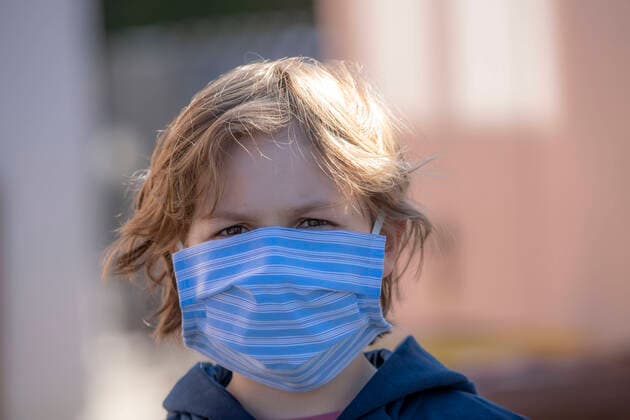 Boy wears a breathing mask, self-sewn, made of cotton, talks on a mobile phone, effects of the corona crisis in Germany,