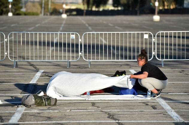 April 1, 2020 - Las Vegas, Nevada, U.S. - A woman prepares a place to sleep in an area marked by painted boxes at a temporary homeless shelter set up in a parking lot at Cashman Center amid the coronavirus pandemic on April 1, 2020, in Las Vegas, Nevada. Local officials opened the makeshift shelter after another local shelter closed when a homeless man staying there tested positive for the coronavirus. Las Vegas USA - ZUMAbk3_ 20200401_zaf_bk3_005 Copyright: xDavidxBeckerx