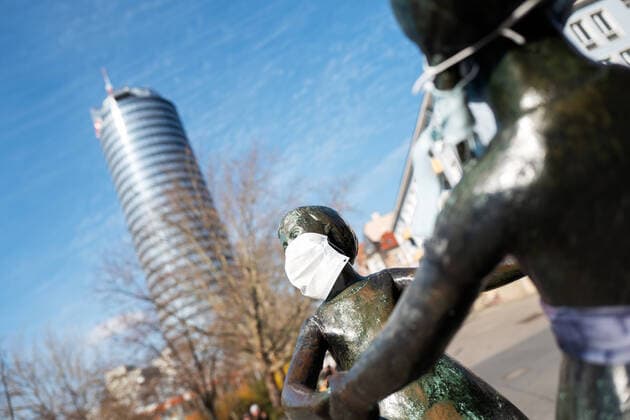 The statue of the two dancing girls in the center of Jena, who were wearing breathing masks by unknown persons In the background of the JenTower Photo from 2 4 2020 downtown Jena