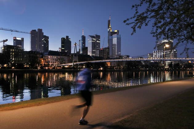 01 04 2020, Frankfurt, DEU Sunset on the Main, office building reflected in the Main A jogger is passing by