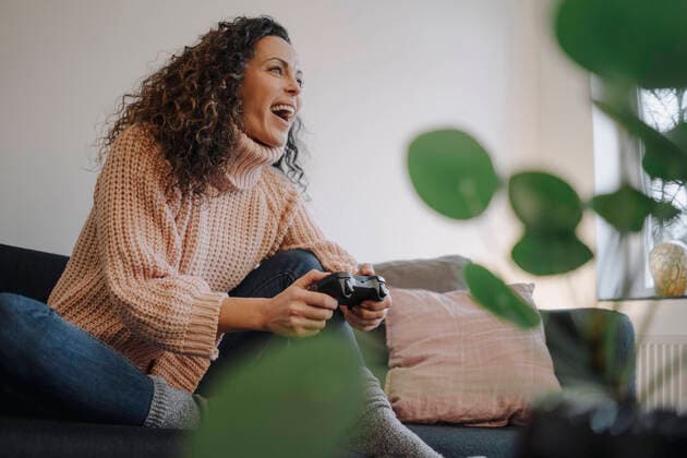 Woman sitting on couch, having fun, playing with a gaming console model released Symbolfoto property released  JOSEF00013