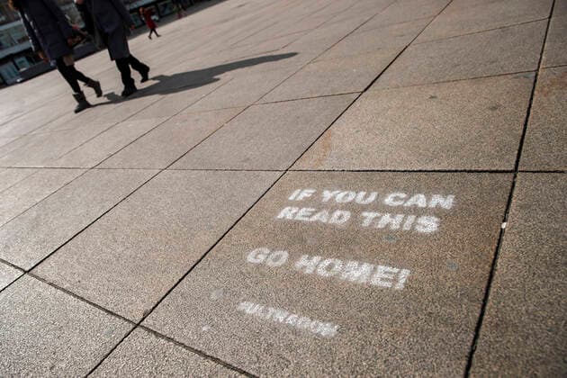 Two people with bags are walking in front of a font If you can read this Go Home at Alexanderplatz in Berlin on April 2, 2020 To slow down the spread of the coronavirus SARS CoV 2, the federal and state governments decided o