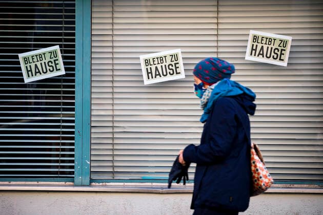 A woman with a face mask runs in front of signs Stay at home in Berlin on April 2, 2020 To slow down the spread of the coronavirus SARS CoV 2, the federal and state governments decided on further restrictions After museums, theatres, sports events etc. were