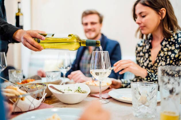 Friends dining in an Indian restaurant, waiter pouring wine in glasses model released Symbolfoto property released  OCMF01046