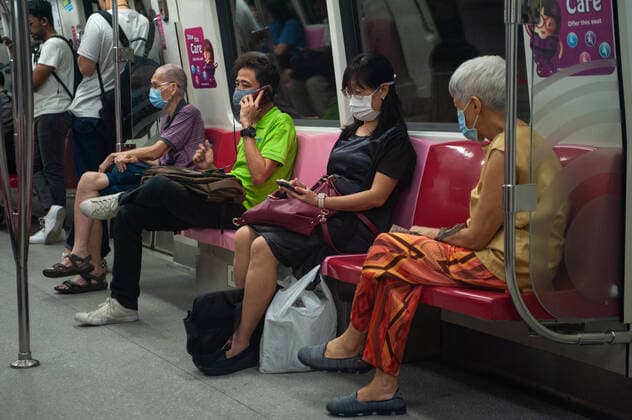 02 04 2020, Singapore, Republic of Singapore, Asia Passengers on a subway train wear respirators to protect themselves from infection with the pandemic corona virus Most people follow the principle of Safe Distance Measures, where an empty seat is left free between them and the seat next to them
