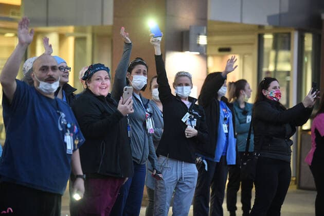 April 3, 2020, Racine, Wisconsin, USA: Emergency room staff members on duty watch and wave as hundreds of cars packed the campus of Ascension All Saints Hospital to show their support to the staff. The event, suggested by a NICU nurse, for cars to parade through the grounds flashing their headlights, was billed as Flashin First Friday because the traditional downtown First Fridays during which stores stay open late was canceled. So many cars came that the parade stalled that most cars just parked facing the hospital buildings and honked their horns for an hour. Racine County reported its first COVID-19 death Friday. Racine USA - ZUMAh154 20200403_znp_h154_023 Copyright: xMarkxHertzbergx