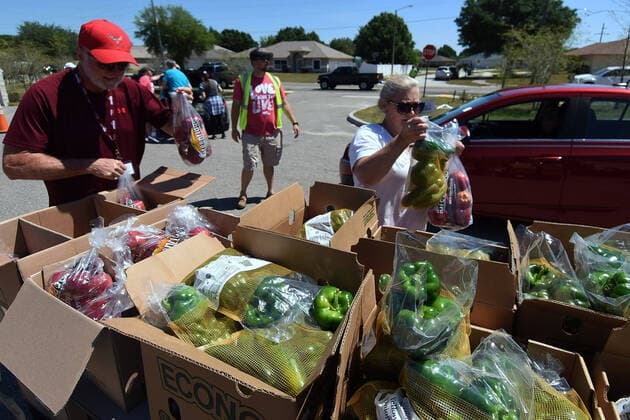 April 3, 2020, Groveland, Florida, United States: Volunteers grab bags of apples and green peppers from the Second Harvest Food Bank of Central Florida for distribution to needy families at a drive through event at the Faith Neighborhood Center near Orlando. The coronavirus pandemic has put thousands of local service employees and theme park workers out of work, placing a strain on area food banks. Groveland United States - ZUMAs197 20200403_zaa_s197_339 Copyright: xPaulxHennessyx