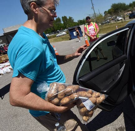 April 3, 2020, Groveland, Florida, United States: A volunteer places a bag of potatoes from the Second Harvest Food Bank of Central Florida into the back seat of a car at a drive through event for needy families at the Faith Neighborhood Center near Orlando. The coronavirus pandemic has put thousands of local service employees and theme park workers out of work, placing a strain on area food banks. Groveland United States - ZUMAs197 20200403_zaa_s197_345 Copyright: xPaulxHennessyx