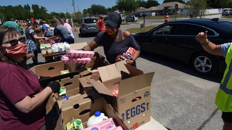 April 3, 2020, Groveland, Florida, United States: Volunteers wearing protective face masks prepare packages of milk, orange juice, and eggs from the Second Harvest Food Bank of Central Florida for distribution to the needy at a drive through event that served over 350 families at the Faith Neighborhood Center near Orlando. The coronavirus pandemic has put thousands of local service employees and theme park workers out of work, placing a strain on area food banks. Groveland United States - ZUMAs197 20200403_zaa_s197_355 Copyright: xPaulxHennessyx
